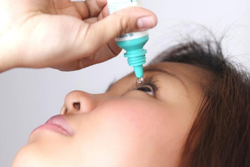 asian woman applying eye drops