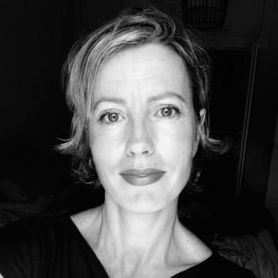 Close-up, black and white selfie of a woman with short, light hair and red lipstick looking directly at the camera