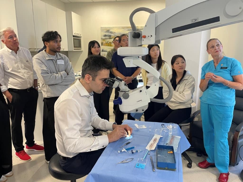 A group of people are watching a surgeon demonstrating refractive surgery using a model eye