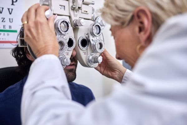 a woman optometrist is doing refraction eye test on a male adult