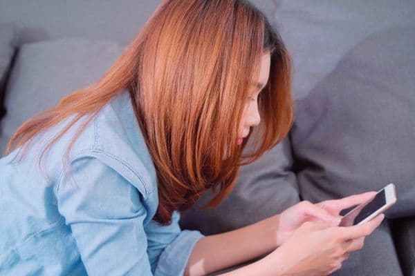 portrait beautiful attractive young smiling asian woman using smartphone while lying sofa