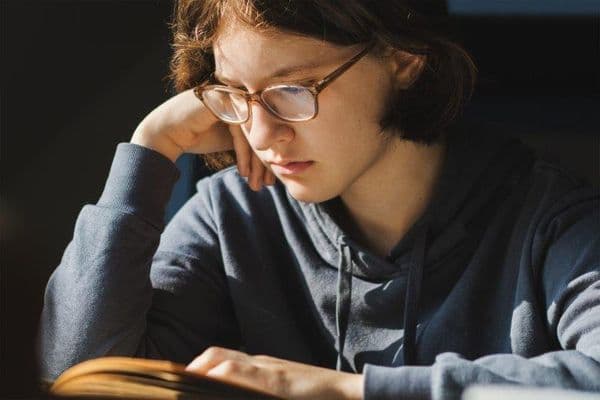 teen glasses reading sad