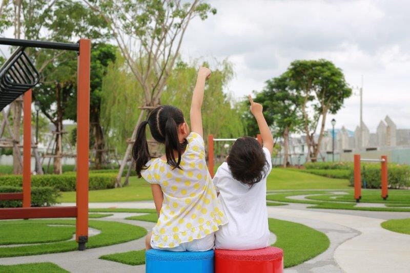 asian sister sitting with little brother garden online